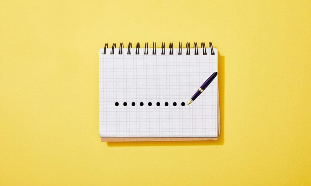 A notebook and pen placed on a vibrant yellow background, showcasing a simple yet elegant stationery setup.