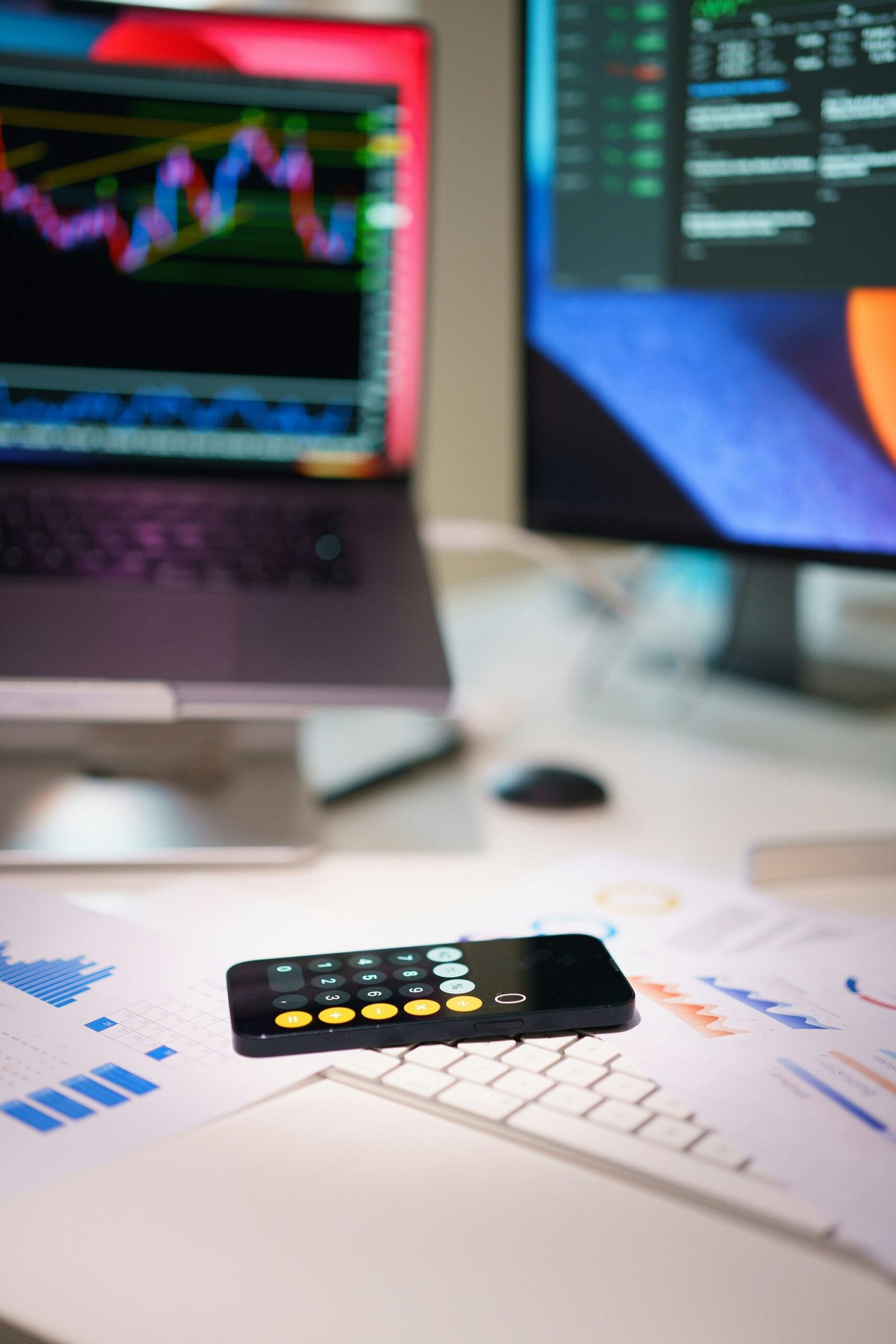 A laptop, phone, and monitor arranged neatly on a desk, showcasing a modern workspace setup.