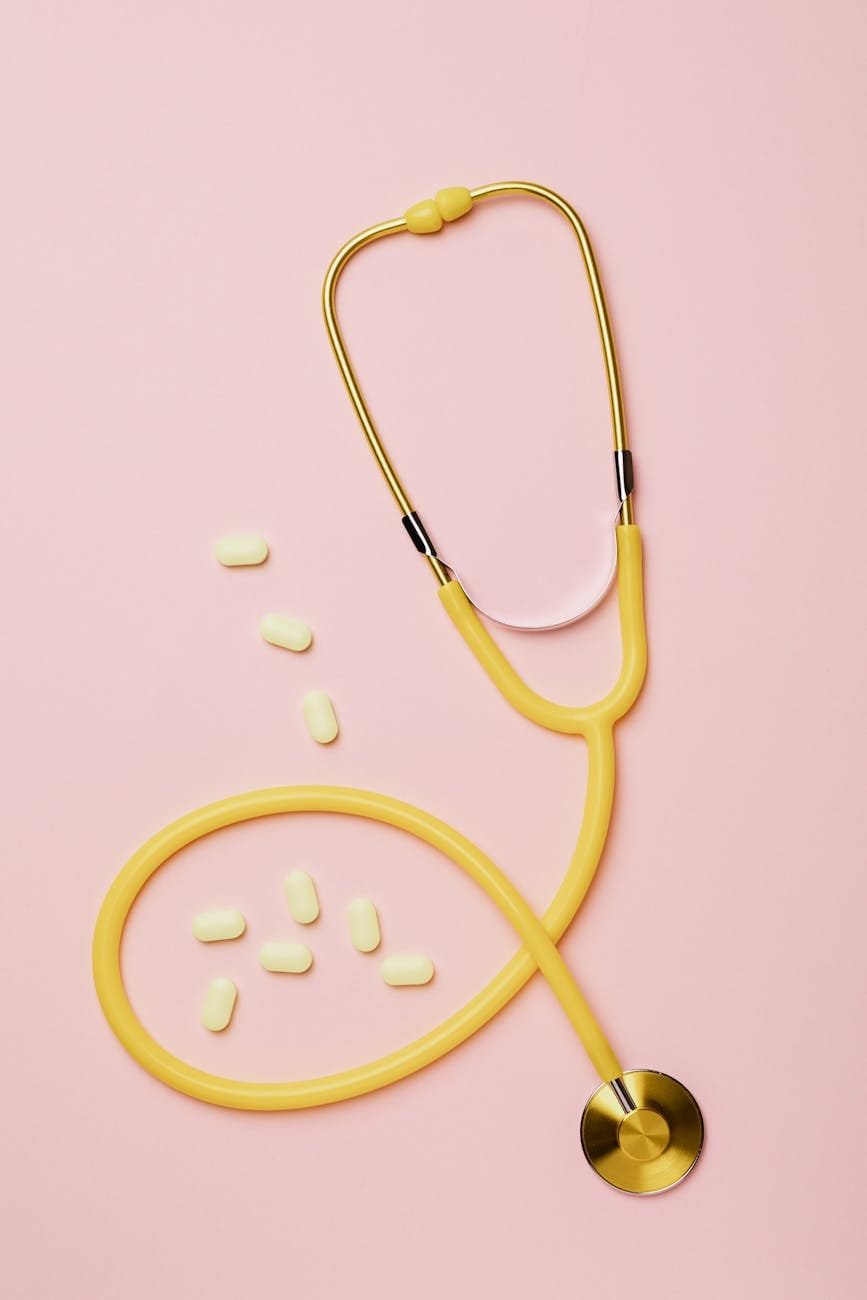 yellow stethoscope and tablets on pink background